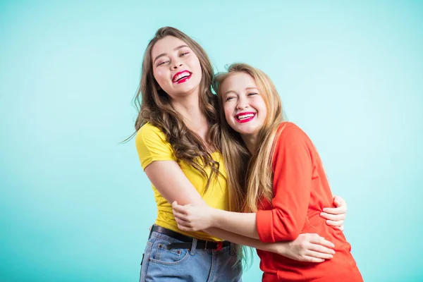Momentos positivos brilhantes felizes de duas meninas elegantes abraçando no fundo azul. Closeup retrato engraçado alegre attarctive jovens mulheres se divertindo, sorrindo, momentos encantadores — Fotografia de Stock
