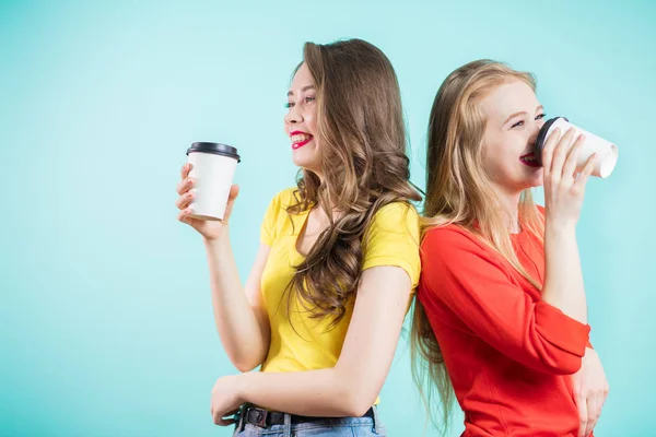 Twee lachende studenten met een kopje koffie. Gelukkig jonge vrouwen lach, rug aan rug — Stockfoto