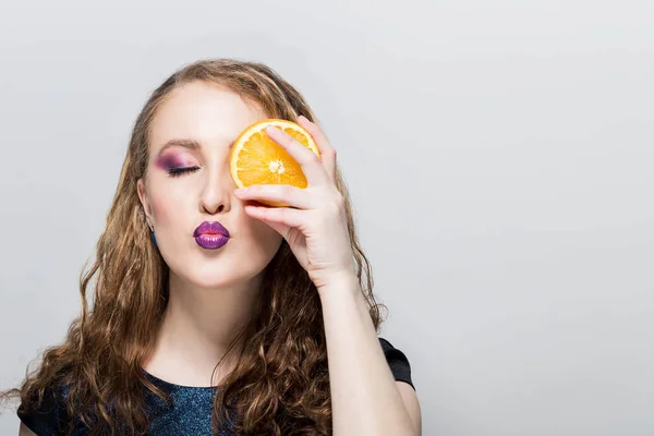 Potret wanita muda menarik dengan jeruk di tangan pada latar belakang putih. Tersenyum dan melihat ke kamera . — Stok Foto