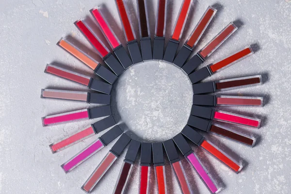 Una gran cantidad de lápices labiales de colores, extendidos en un círculo sobre un fondo blanco gris claro —  Fotos de Stock