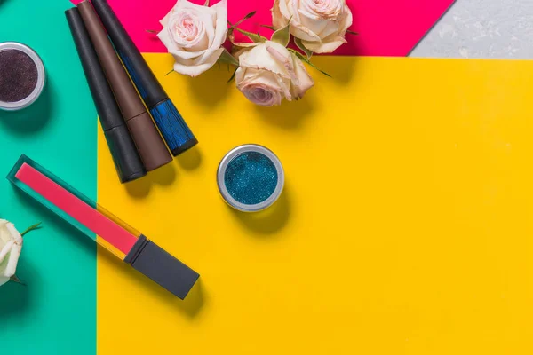 Make-up profesional cantik tri-warna pada latar belakang cerah, mawar, lipstik, eyeshadow, maskara, close-up, latar belakang kuning, ruang penyalinan — Stok Foto