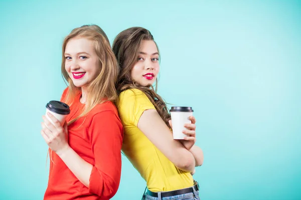 Dos mujeres sonriendo espalda con espalda con tazas de papel de café —  Fotos de Stock