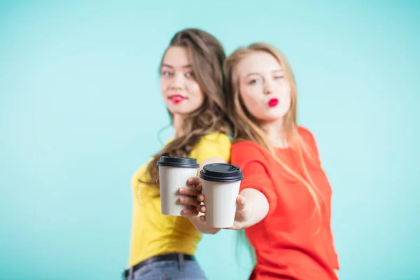 Twee kopjes koffie papier op de voorgrond, in focus. Jonge meisjes die hand in hand — Stockfoto