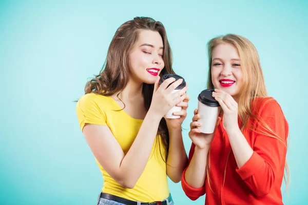 Dos chicas sonrientes tienen tiempo de café sobre fondo azul —  Fotos de Stock