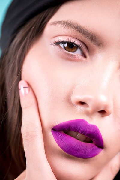 Close up face of a beautiful young brunette woman with professional makeup, well groomed face, purple lips. Fashion, cosmetics, fashion, luxury