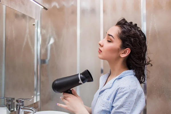 Schöne junge Frau trocknet Haare nach der Dusche im hellen Badezimmer zu Hause — Stockfoto