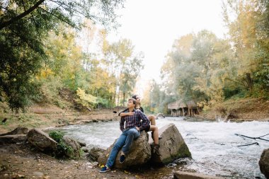 Bir kayaya oturan güzel genç çift doğa nehre yakın: