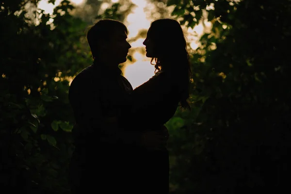 Silhueta de um jovem casal ao ar livre à noite ao pôr do sol — Fotografia de Stock