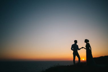 Deniz, bir adam ve bir kadın tutun eller güzel günbatımında bak birbirlerine, bir aşk