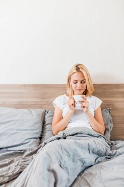 Kahve içme yatağın üstüne oturan kadın