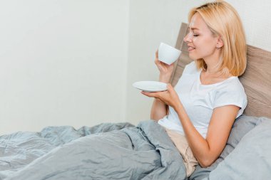 Kahve içme yatağın üstüne oturan kadın