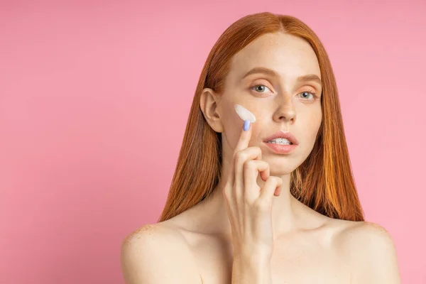 Beautiful young ginger woman with cream on face