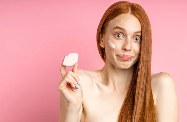 Potret wanita muda yang mengenakan krim wajah dan wajah bersih dengan spons — Stok Foto
