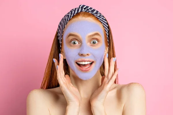 Beautiful woman with facial mask on pink background — Stock Photo, Image