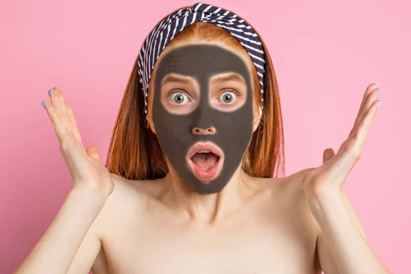 Vacker kvinna med ansiktsmask på rosa bakgrund — Stockfoto