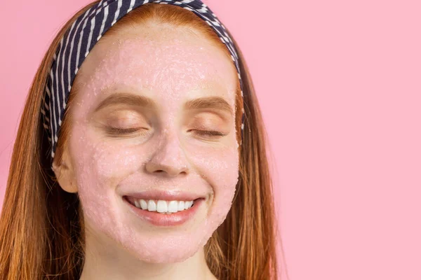 Hermosa mujer con máscara facial sobre fondo rosa — Foto de Stock