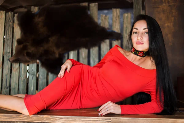 En vacker kvinna i en röd klänning är liggande i baren — Stockfoto