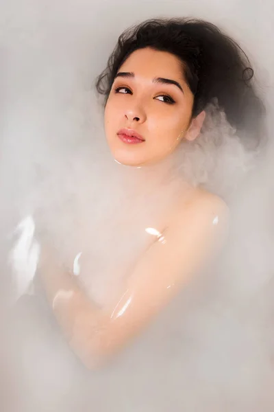 Mooi jong sexy meisje met donker haar en natuurlijke make-up, neemt bad met melk, schoonheidssalon en spa voor vrouw. — Stockfoto