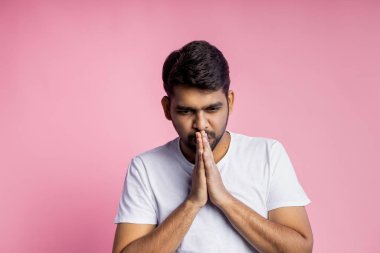 Pembe arka planda duran yakışıklı Hintli adamın portresi.