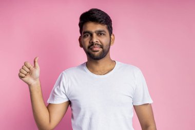 Pembe arka planda duran yakışıklı Hintli adamın portresi.