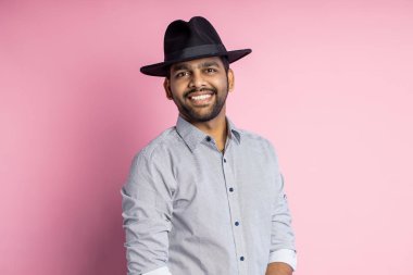 Pembe arka planda duran yakışıklı Hintli adamın portresi.