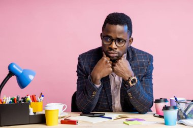 İş yerinde oturan, mali sorunları olan, düşünen, uzaktan bakan yorgun, koyu tenli genç menajerin portresi. İnsanlar, iş, aşırı çalışma kavramı.