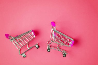 Pembe arka planda iki boş oyuncak vagonunu kapat, mesaj için boşluğu kopyala. Satış, alışveriş merkezi, alışveriş konsepti. Alışveriş arabası koleksiyonu. Üst görünüm.