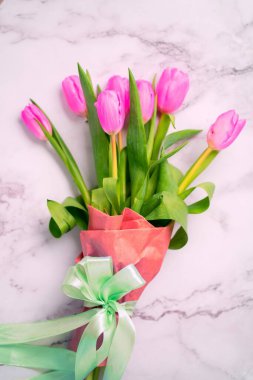 Beyaz mermer bir zemin üzerinde pembe lale buketi. Metin ve üst görünüm için bahar fotokopi alanı var.