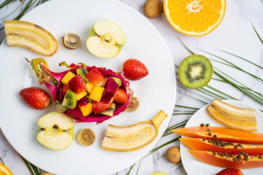 Masanın üzerindeki taze meyveli, tropikal egzotik meyvelerden sağlıklı bir kahvaltı. Lezzetli atıştırmalıklar, seyahat, tatil, vitaminler, yaz konsepti. Üst manzara, düz uzanma.