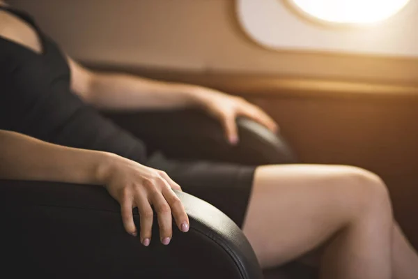 Cropped shot of businesswoman with flight fear in private jet. Selective focus of terrified woman sitting clutching the arms of the chair in private plane. Aerophobia concept.