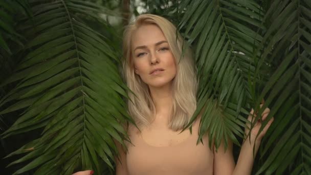 Mujer en traje de baño sobre fondo de plantas tropicales — Vídeo de stock