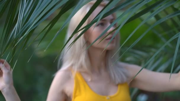 Mujer en traje de baño sobre fondo de plantas tropicales — Vídeos de Stock