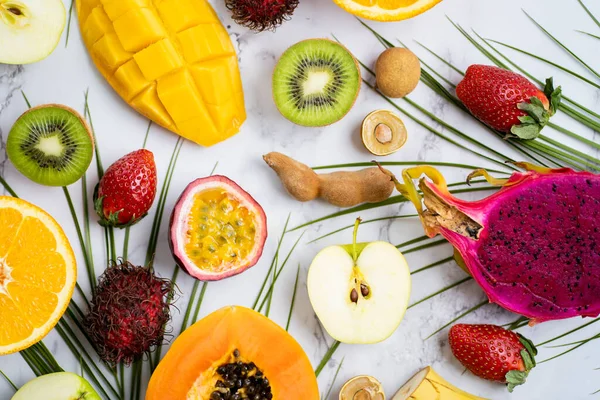 Exotic fruits and tropical leaves on table — Stock Photo, Image