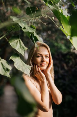 Tropik bitki arka planında mayo giymiş bir kadın.