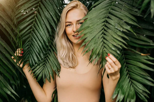 Vrouw in badpak op tropische planten achtergrond — Stockfoto