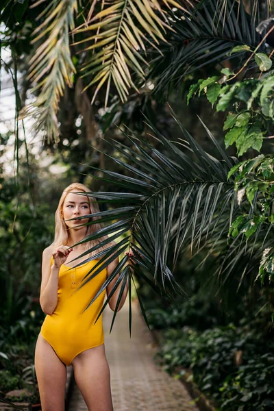 夏天，一位穿着黄色泳衣的金发美女在异国情调的森林里的性感时尚画像 — 图库照片