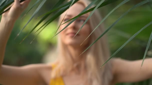 Mujer en traje de baño sobre fondo de plantas tropicales — Vídeos de Stock