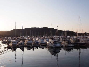 BODO, NORway, HAZİRAN 2019: Güneşli yaz günbatımında açık mavi gökyüzü ile Salten bölgesindeki Avrupa şehrindeki yat ve teknelerin karanlık görüntüsü.