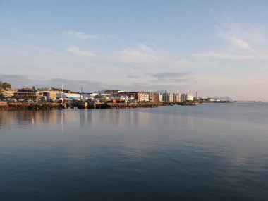 Norveç 'in Salten bölgesindeki Avrupa kenti Bodo' da gezinti güvertesinde sakin bir manzara, 2019 yılında güneşli bir yaz günü Temmuz 'da gün batımında açık mavi bir gökyüzü.