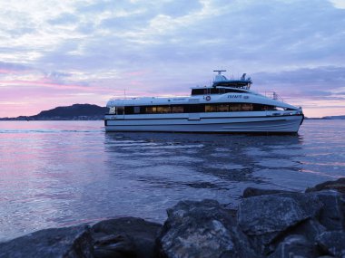 Norveç 'in Romsdal kentindeki Avrupa Alesund kasabasından mavi saatte görülen körfez manzaralı bir gemi ve kayalar.
