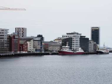 BODO, NORWAY on JULY 2019: Two ships and modern buildings in european city at Salten region with cloudy sky in cold summer day in the morning.