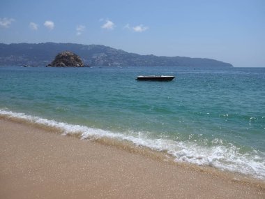 Meksika 'daki Acapulco şehrinde beyaz dalgalı ve tekneli sahil.