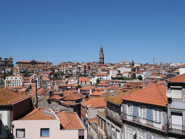 Houses with red roofs and tower in historical Ribeira area of european Porto city in Portugal, clear blue sky in 2019 warm sunny summer day on September.