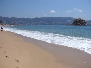 Meksika 'nın Guerrero bölgesindeki ACAPULCO şehrinde beyaz dalgalar ve kayalarla dolu plaj ve açık mavi gökyüzü 2018' de güneşli kış günü, Kuzey Amerika 'da Mart ayında.