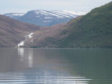 Norveç 'in Nordland ilçesindeki Avrupa Svartisen buzulu yakınlarındaki manzaralar üzerindeki Svartisvatnet gölü ve şelalesine, 2019' un soğuk yaz günü bulutlu gökyüzüne bakın..