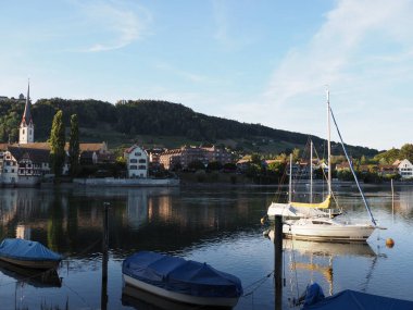 STEIN am RHEIN, SWITZERLAND on AUGUST 2018: Boats and St. George's Abbey at Rhine River at european town, canton Schaffhausen, clear blue sky at evening.