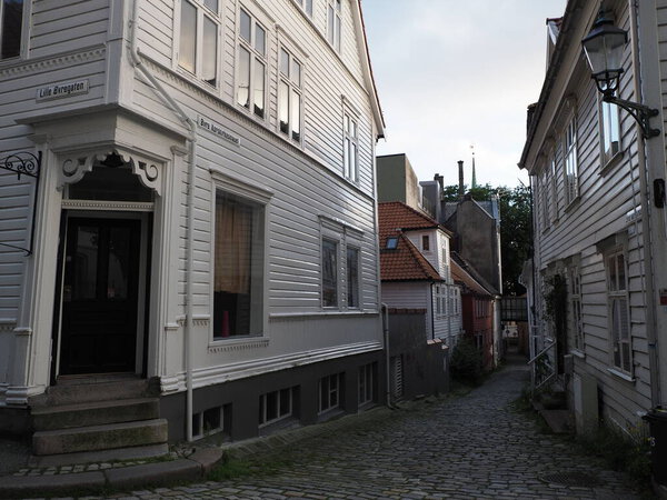 Narrow street with white houses in city center of european town at Hordaland region in Norway, cloudy sky in 2019 warm summer day on July.