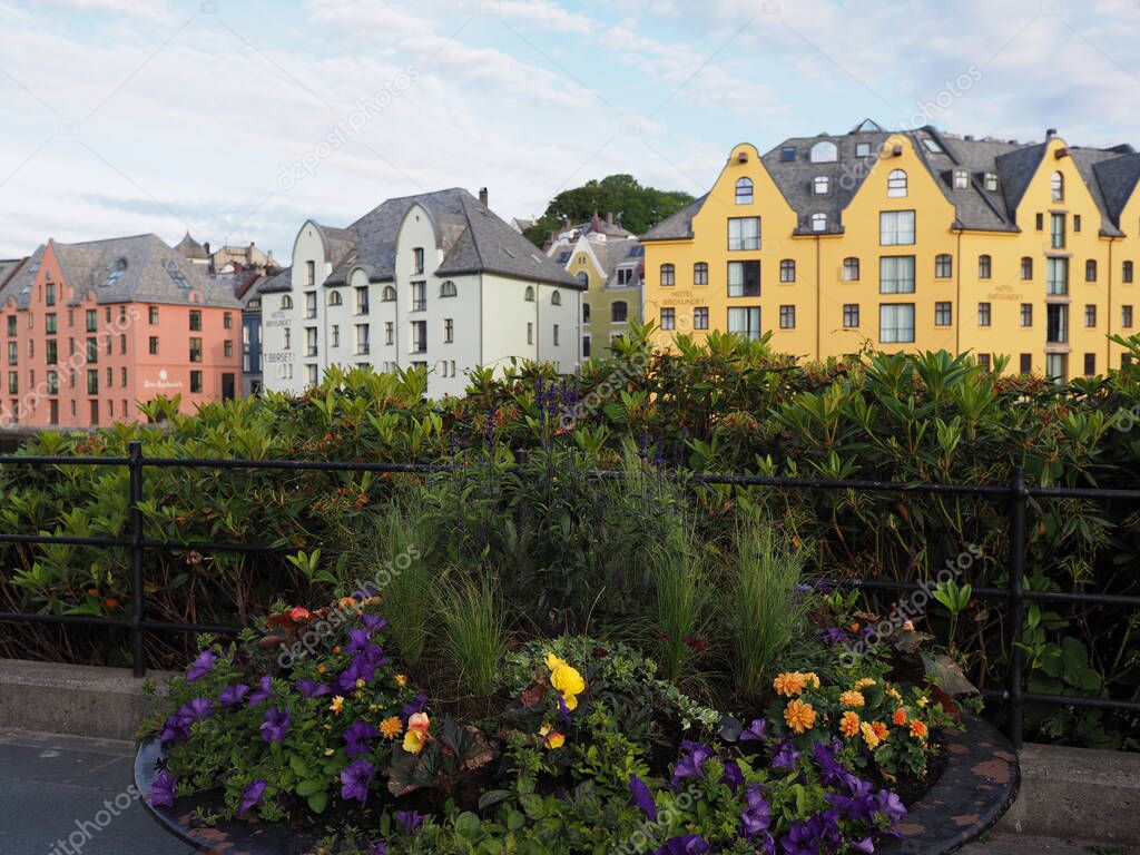 ALESUND, NORWAY on JULY 2019: Plants and buildings of european town at Romsdal region with cloudy sky in warm summer day in the morning.
