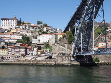 Portekiz 'in Avrupa PORTO şehrindeki Douro nehri üzerindeki Ribeira bölgesinin tarihi binaları ve çift katlı metal köprü, 2019 yılında güneşli bir yaz günü açık mavi gökyüzü.