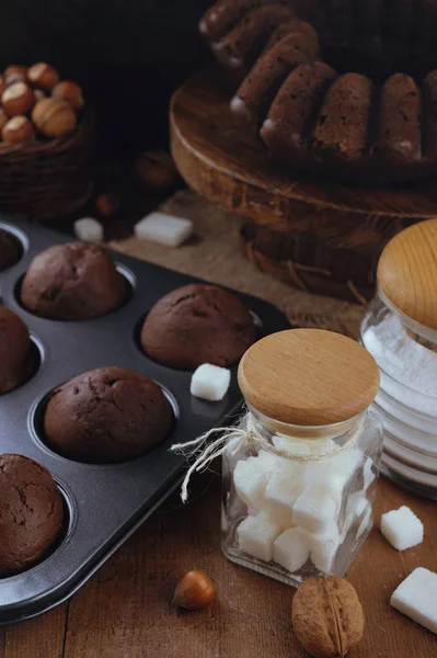 Bolo de chocolate e pequenos cupcakes com nozes na mesa rústica — Fotografia de Stock